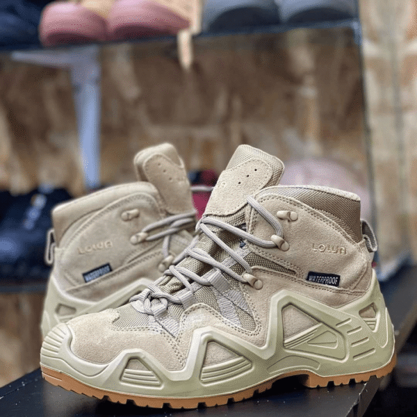 Desert Lowa lowcut hiking boot in tan color on a rocky trail background